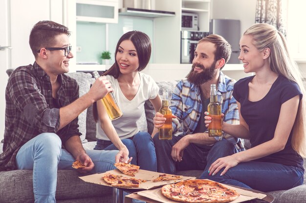 Amis faisant la fête ensemble à l'intérieur en train de manger de la pizza