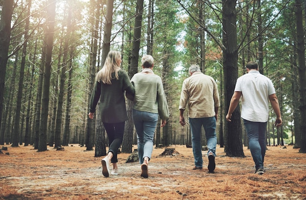 Photo amis de la famille et aventure en forêt avec parents et enfants adultes marchant dans la nature pour des randonnées en plein air amusantes et des arbres en vacances de bien-être courir en couple et voyager hommes et femmes dans les bois