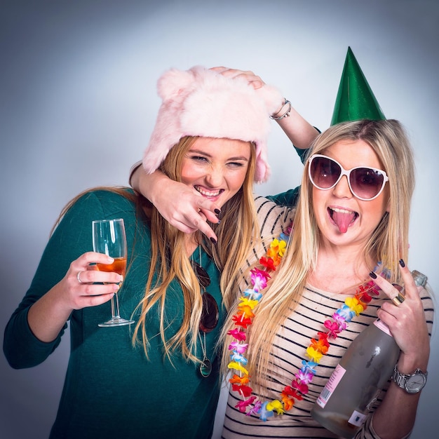 Amis fête de l'alcool et de la boisson par fond de studio pour célébrer le nouvel an et le bonheur Happy boit des femmes et un chapeau drôle avec une bouteille en verre et un câlin pour des acclamations festives sourire et célébrer