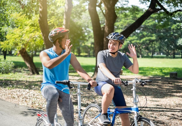 Des amis font des gestes en faisant du vélo contre des arbres