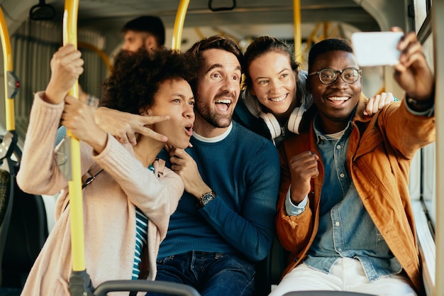 Amis gais prenant le selfie avec le téléphone intelligent tout en faisant la navette en bus