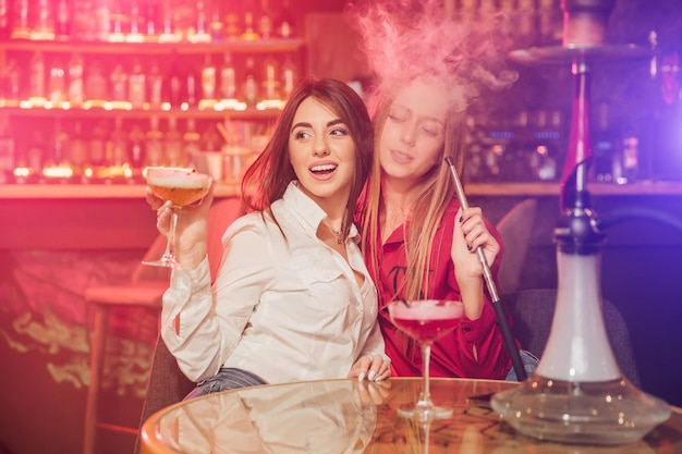 Des amis heureux applaudissent et boivent des cocktails à la fête sur la plage en plein air Les jeunes de la génération Y s'amusent le week-end la nuit d'été Concept de mode de vie et de vie nocturne des jeunes Accent principal sur les gars de gauche