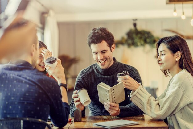 Photo des amis heureux assis à table dans un café