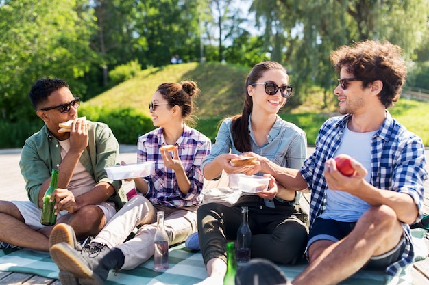 Des amis heureux au pique-nique dans le parc d'été.