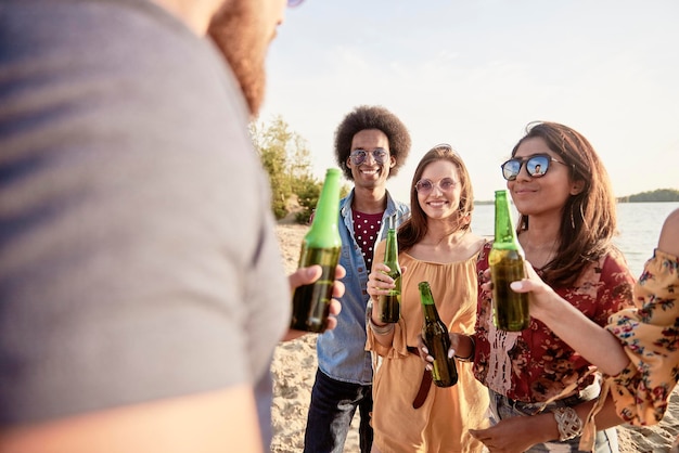 Des amis heureux avec des bouteilles de bière sur la plage.