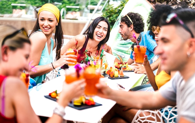 Amis heureux buvant des cocktails à la fête de la piscine