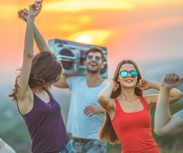 Les amis heureux dansant sur le fond du lever du soleil