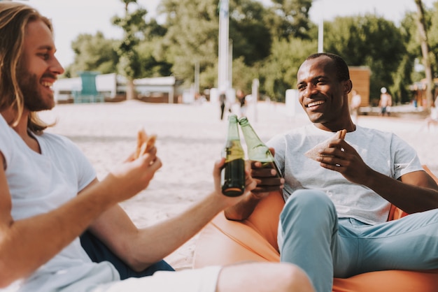 Des amis heureux mangent et boivent sur la plage.