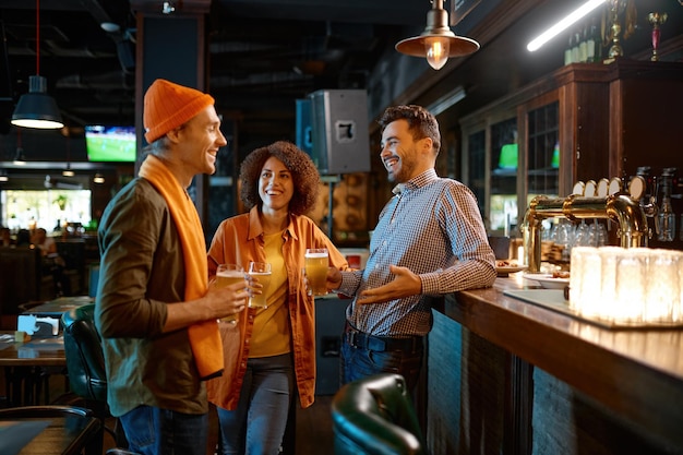 Amis heureux parlant tout en buvant de la bière au comptoir du bar