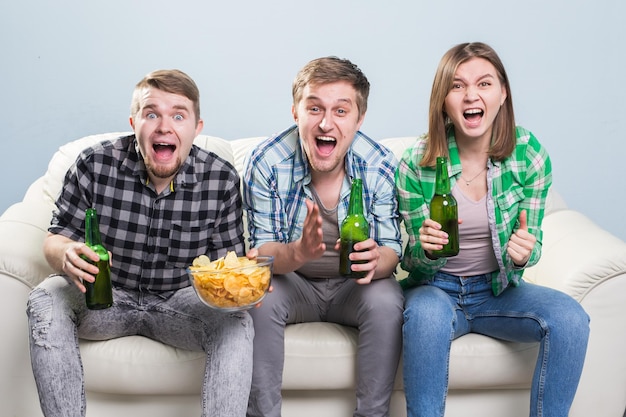 Des amis heureux qui détournent leur regard en s'asseyant sur le canapé.