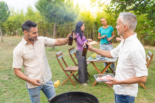 Amis heureux riant et portant un toast avec un grand sourire autour du barbecue Personnes souriantes mangeant sur le patio de la maison en été Concept de joie