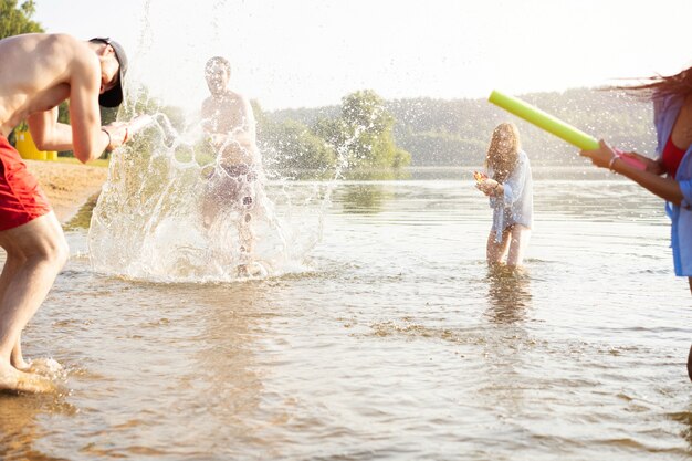 Des amis heureux se battent avec des pistolets à eau - Jeunesse, mode de vie estival et concept de vacances