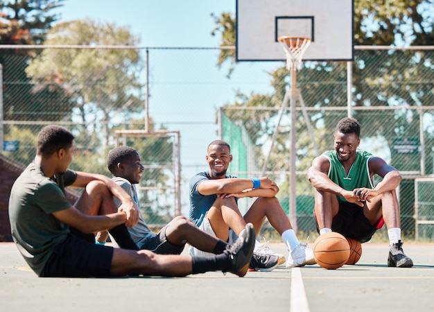 Les amis et les hommes du terrain de basket-ball font une pause et font la conversation sociale des sports d'équipe et se détendent dans l'aire de jeux communautaire Les joueurs de basket-ball se reposent et les Noirs ensemble après l'entraînement et le match de l'équipe de jeu