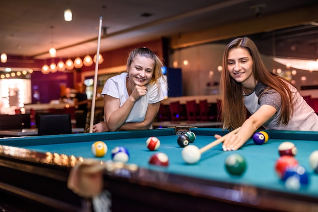 Amis jouant au billard visant sur ball in pub