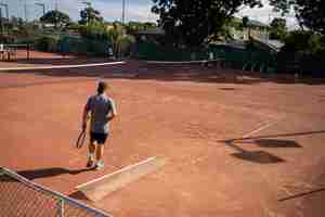 Photo des amis jouant au tennis sur un terrain d'argile arrosant et emballant un terrain dargile faisant l'entretien d'un terrain de tennis