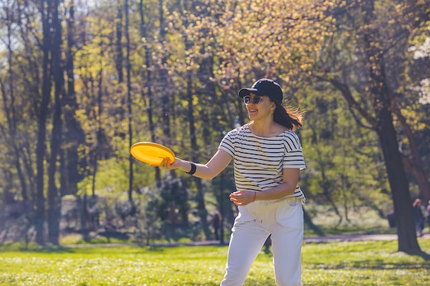 Des amis jouent au frisbee au printemps ensoleillé dans un parc public