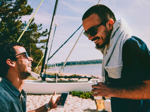 Photo des amis joyeux en train de parler sur la plage pendant l'été.