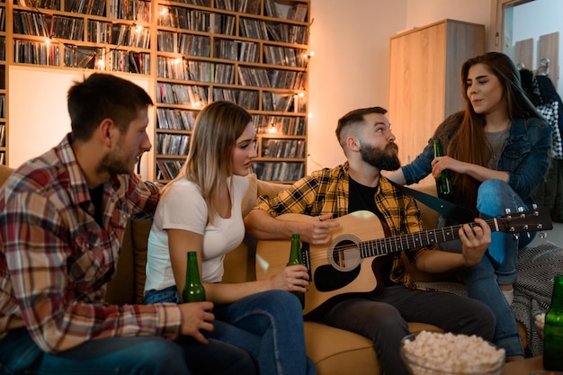 Amis lors d'une fête à la maison jouant de la guitare et buvant de la bière