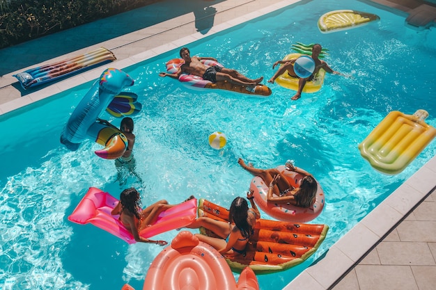 Amis en maillot de bain dans la piscine bronzant