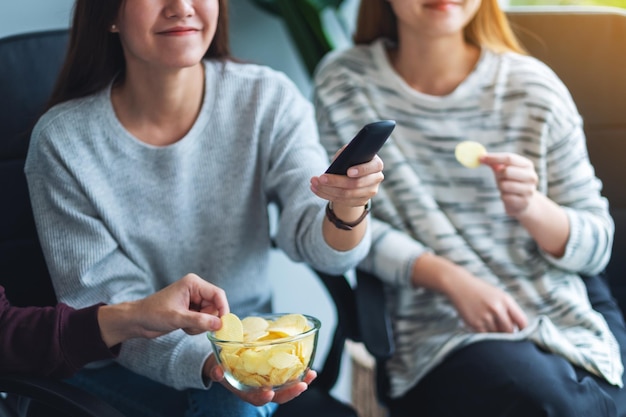 Amis mangeant des croustilles en regardant la télévision ensemble