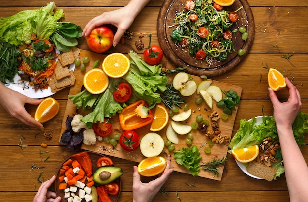 Les amis mangent des aliments sains ensemble. Table à dîner végétalienne. Femmes à la maison ensemble, vue de dessus, mise à plat