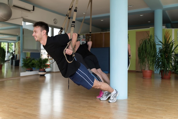 Amis masculins et féminins travaillant avec Trx in Gym