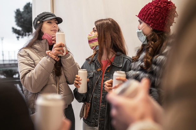 Amis avec des masques s'amusant à embrasser les mains sur les épaules