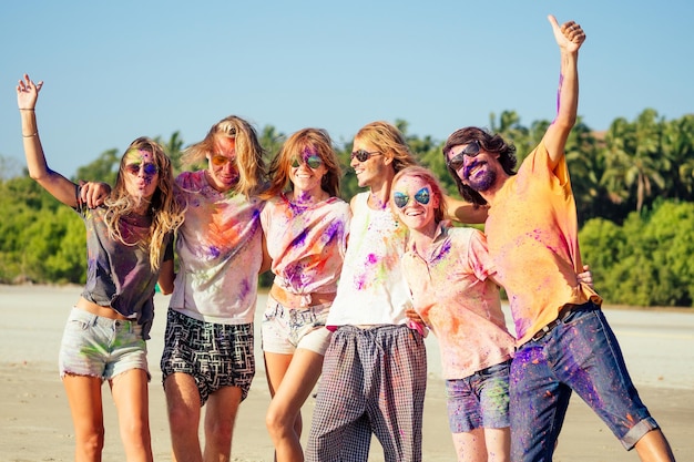 Amis métisses multiculturels multinationaux dans la poussière de holi sur la plage de Goa