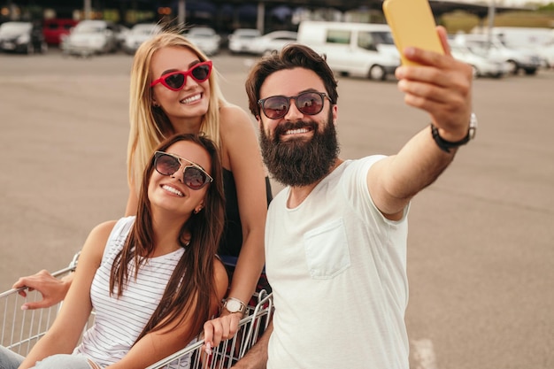 Amis modernes ravis prenant selfie pendant le shopping