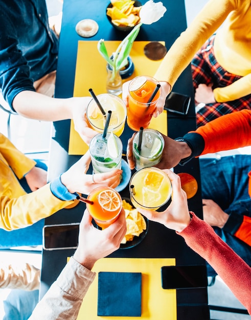 Photo amis multiculturels acclamant et buvant des cocktails au bar-restaurant