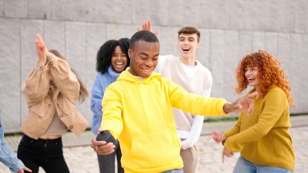 Photo des amis multiethniques heureux dansent excités dans la ville