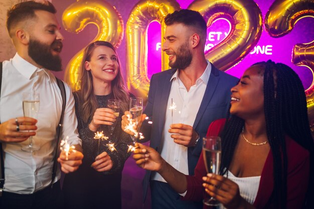 Photo amis multiraciaux célébrant le nouvel an avec du champagne et des cierges magiques