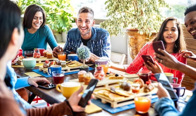 Photo amis multiraciaux interagissant avec un téléphone portable au café-bar