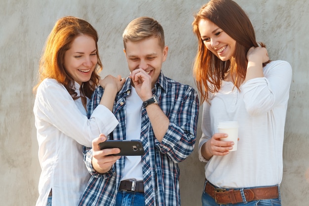 Des amis parlent en plein air et utilisent leurs smartphones