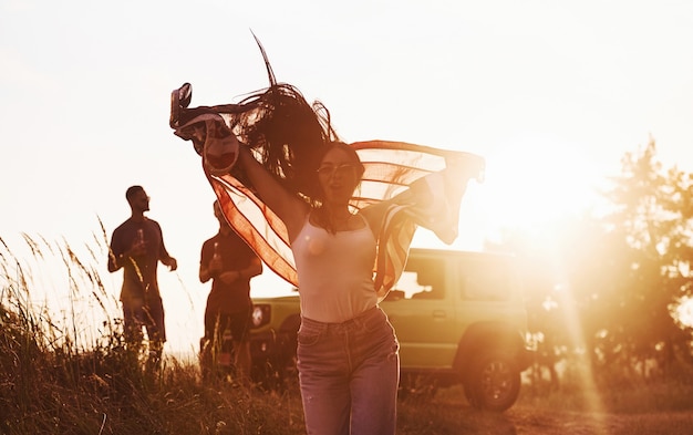 Les amis passent un bon week-end à l'extérieur près de leur voiture verte avec le drapeau américain