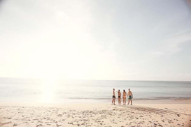 amis sur la plage l'été au bord de la mer / joyeuse compagnie de jeunes amis, vue d'été