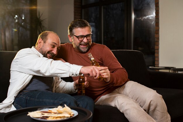 Amis de plan moyen avec des boissons et de la nourriture