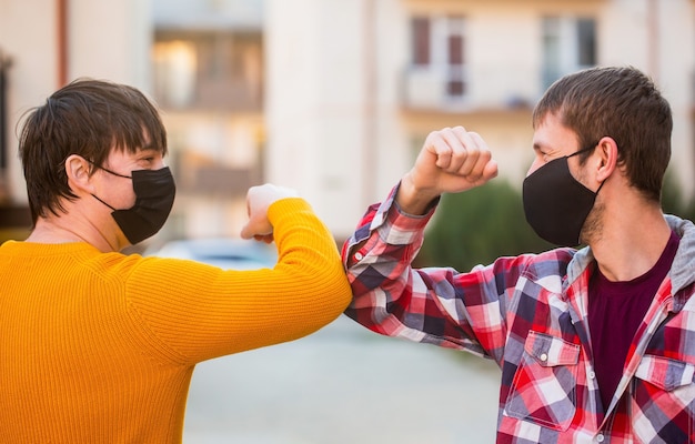 Des amis portant un masque médical de protection sur son visage saluent leurs coudes en quarantaine