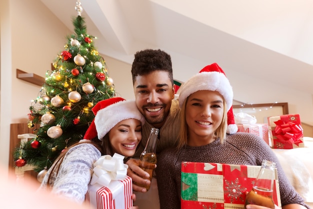 Amis prenant selfie avec des cadeaux et de la bière dans les mains. s. Concept de vacances de Noël.