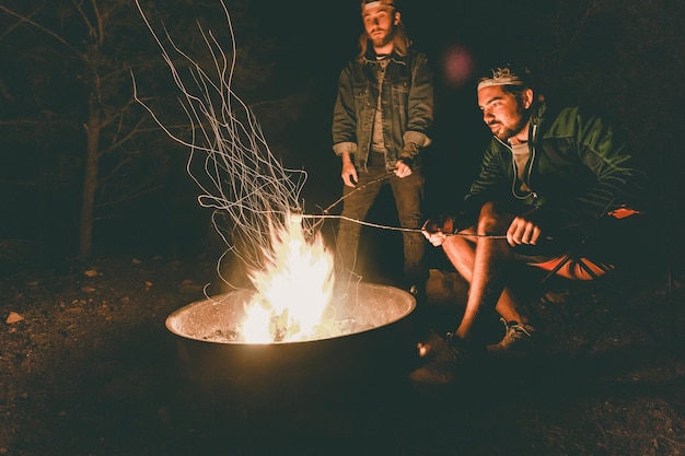 Des amis près d'un feu de joie au camping