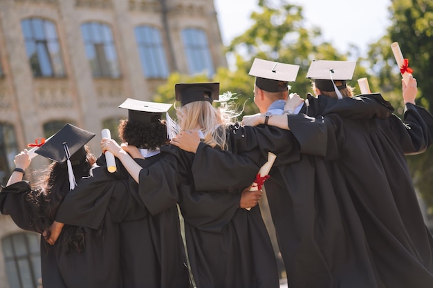 Amis proches. Des diplômés portant des casquettes de maître s'étreignant côte à côte dans la cour de l'université.