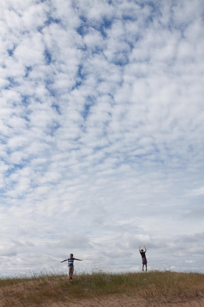 Des amis qui marchent sur le champ contre un ciel nuageux