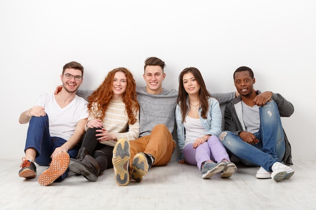 Amis qui rient heureux, étudiants divers en décontracté ensemble à l'intérieur. Fond blanc, espace de copie