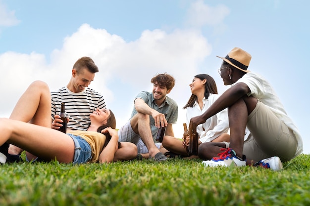 Des amis qui se détendent à l'extérieur dans la nature, qui rient, qui s'amusent, qui boivent une bière ensemble.