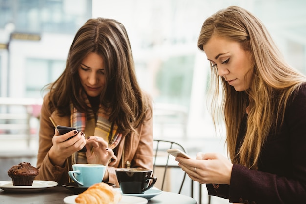 Amis en regardant smartphone dans un café