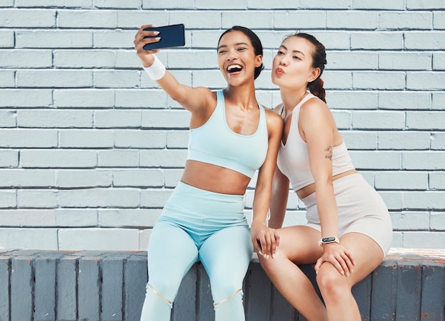 Amis de remise en forme téléphonent selfie et photo pour le contenu des influenceurs des médias sociaux et une séance d'entraînement heureuse après l'exercice et l'entraînement par un mur de briques