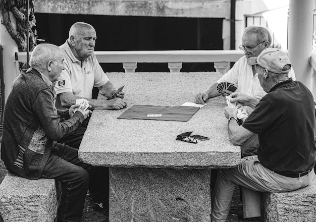 Amis à la retraite jouant aux cartes à une table en pierre du village