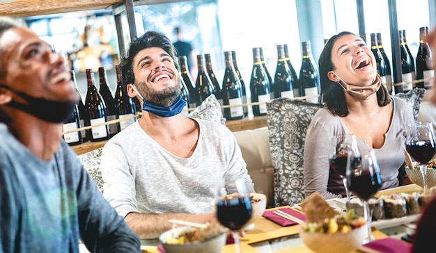 Amis s'amusant au bar à vin avec masque facial ouvert