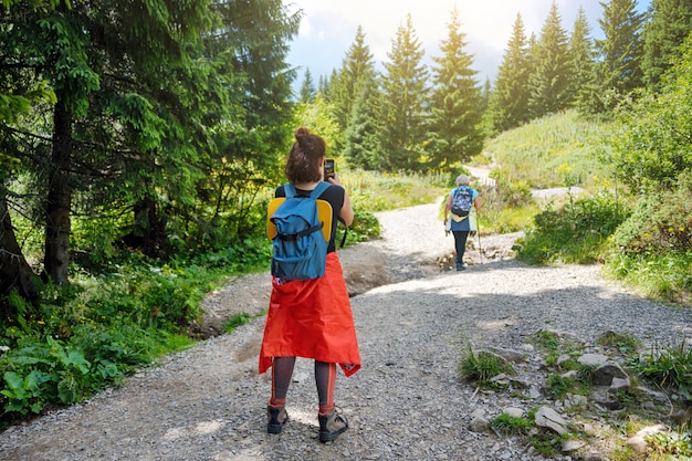 Amis s'amusant ensemble, femme prenant une photo de son amie en randonnée dans les montagnes.