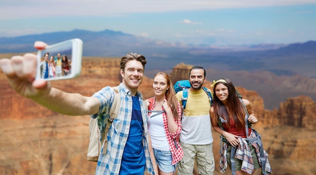 des amis avec un sac à dos prenant un selfie par smartphone